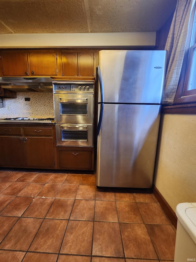 kitchen with stainless steel fridge, gas stovetop, backsplash, and double oven