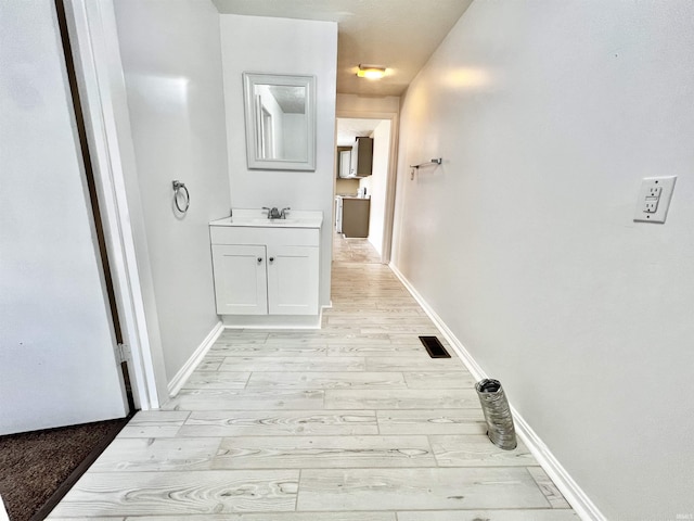 hallway with light hardwood / wood-style flooring and sink