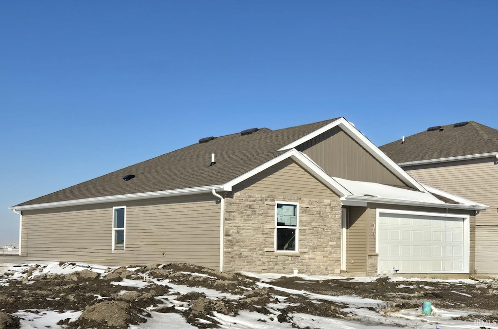 exterior space featuring stone siding, a shingled roof, and an attached garage