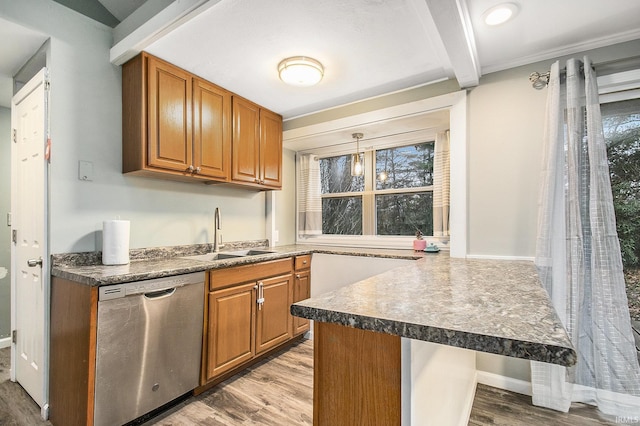 kitchen featuring a kitchen bar, stainless steel dishwasher, sink, light hardwood / wood-style flooring, and hanging light fixtures