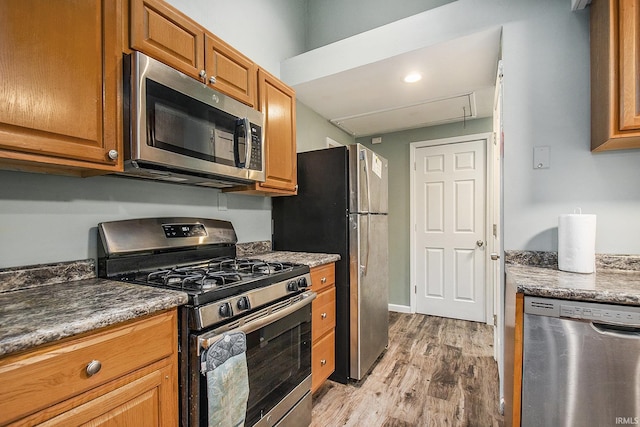 kitchen featuring dark stone counters, stainless steel appliances, and light hardwood / wood-style floors