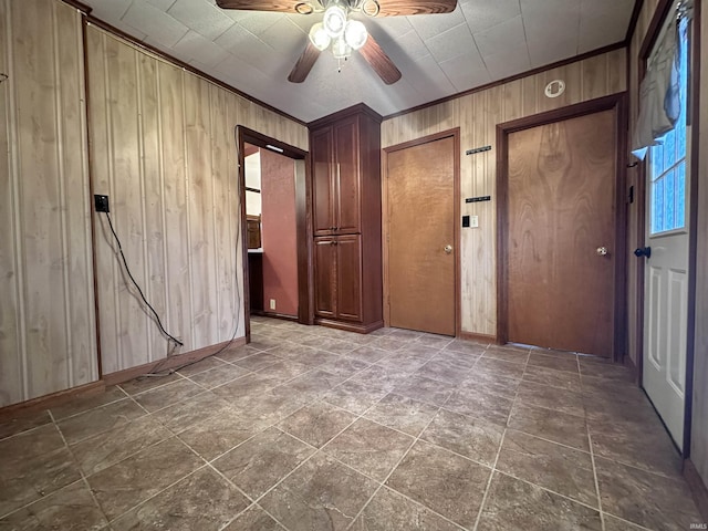 unfurnished room featuring ceiling fan, ornamental molding, and wooden walls