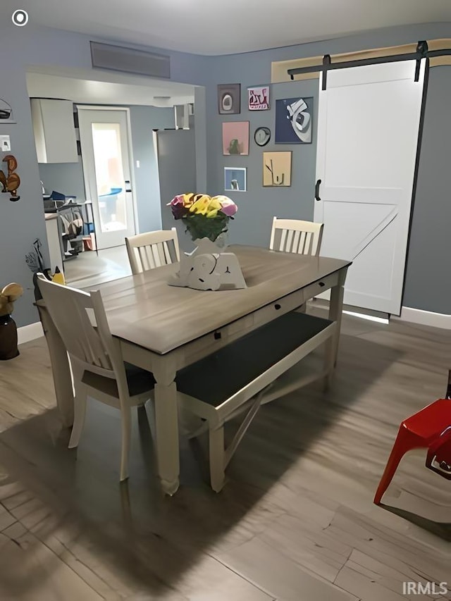 dining room featuring a barn door and light wood-type flooring