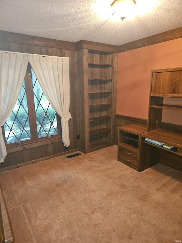 home office with carpet floors, a textured ceiling, and wooden walls