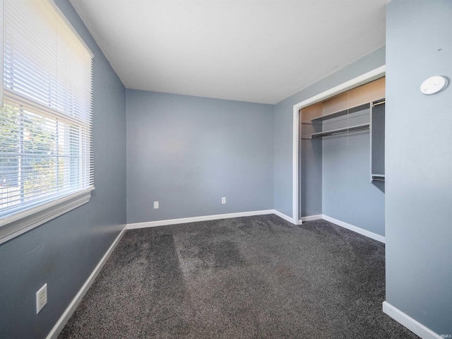 unfurnished bedroom featuring dark carpet and a closet