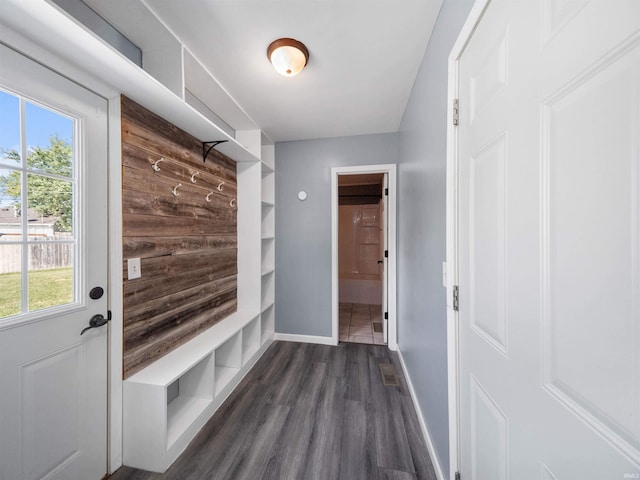 mudroom featuring built in shelves, wooden walls, and dark wood-type flooring