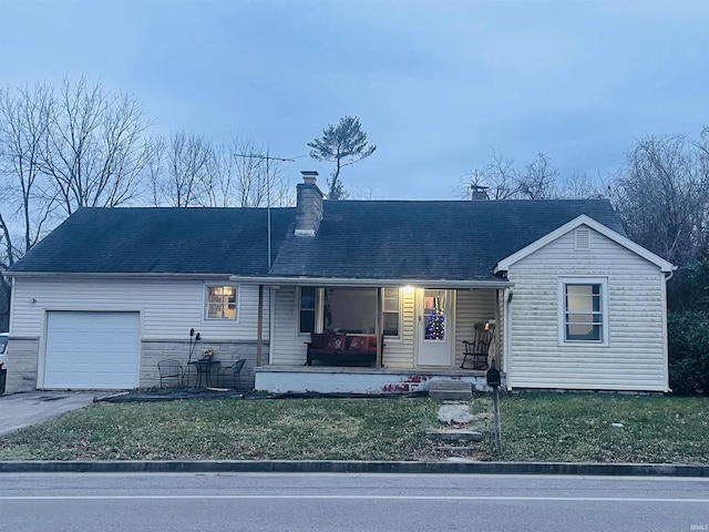 view of front of house featuring covered porch, a garage, and a front yard