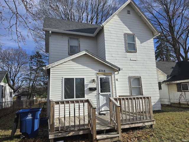 back of property featuring a deck and a lawn