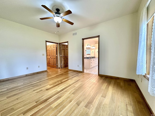 unfurnished bedroom featuring ensuite bath, ceiling fan, a spacious closet, light hardwood / wood-style floors, and a closet