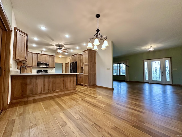 kitchen with kitchen peninsula, pendant lighting, light hardwood / wood-style flooring, and black fridge