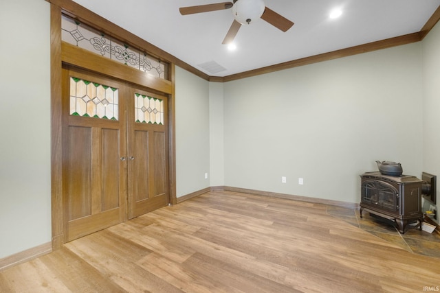 entryway with hardwood / wood-style floors, a wood stove, and ornamental molding