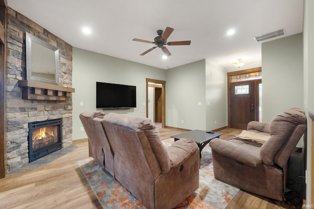 living room with a fireplace, light hardwood / wood-style flooring, and ceiling fan