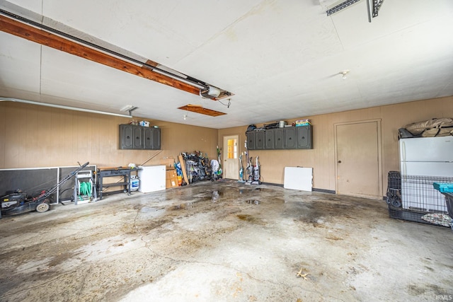 garage featuring white fridge and wood walls