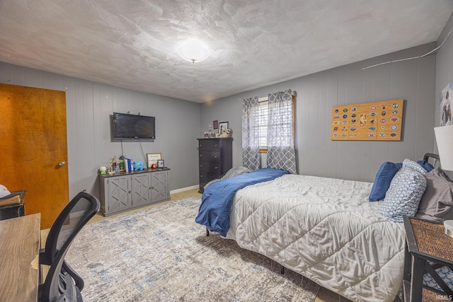 bedroom featuring a textured ceiling and wooden walls