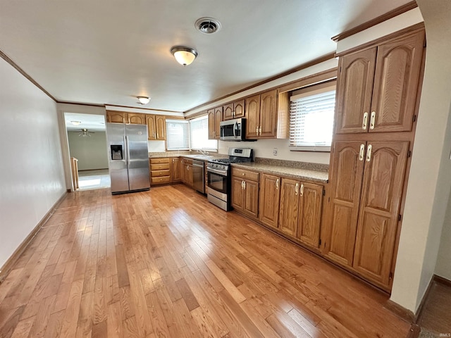 kitchen featuring crown molding, appliances with stainless steel finishes, and light hardwood / wood-style flooring