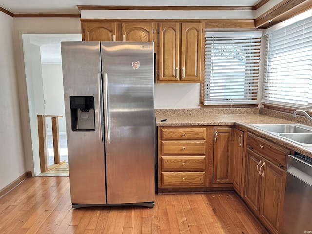 kitchen featuring ornamental molding, stainless steel appliances, light hardwood / wood-style floors, and sink