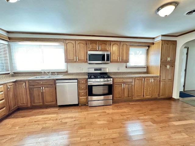 kitchen with crown molding, sink, light hardwood / wood-style floors, and appliances with stainless steel finishes