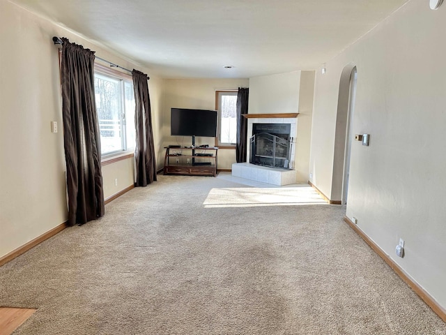 unfurnished living room featuring carpet floors and a tiled fireplace