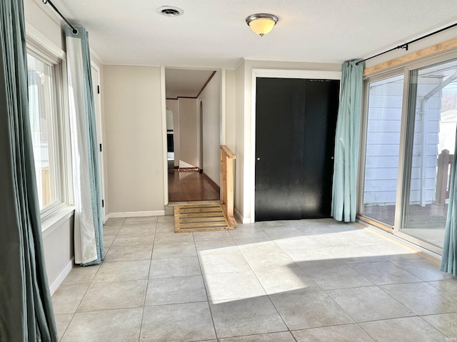 hall with a healthy amount of sunlight, light tile patterned flooring, and crown molding