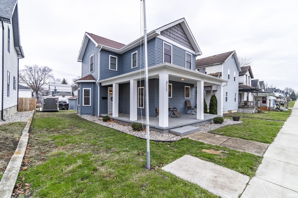 rear view of house with covered porch and a yard