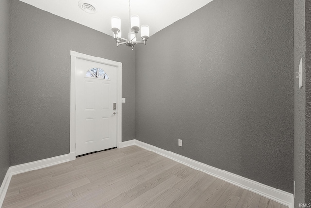 foyer entrance featuring light hardwood / wood-style flooring and a chandelier