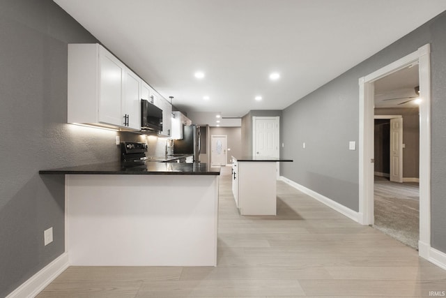 kitchen with kitchen peninsula, a kitchen island, black appliances, light hardwood / wood-style floors, and white cabinetry