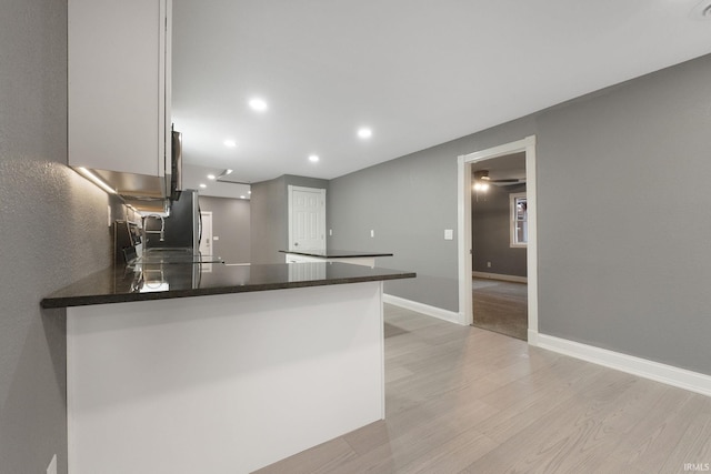 kitchen featuring kitchen peninsula, white cabinetry, and light hardwood / wood-style flooring