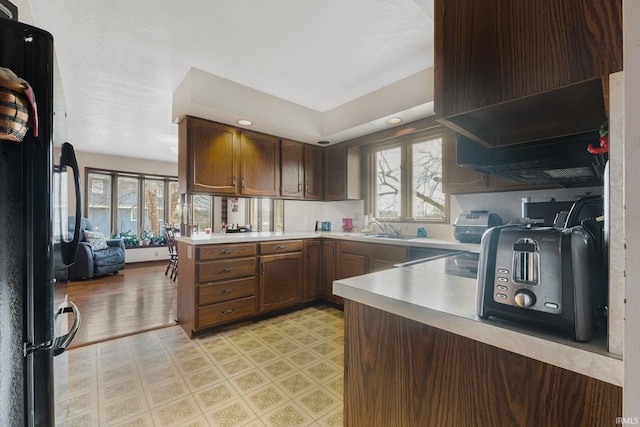 kitchen featuring kitchen peninsula, black fridge, sink, and a healthy amount of sunlight