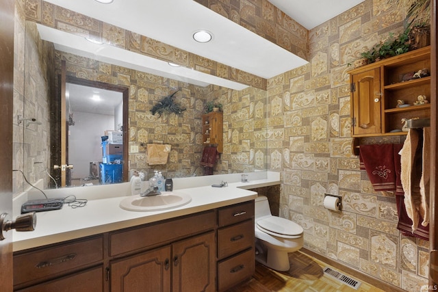 bathroom featuring parquet flooring, vanity, and toilet