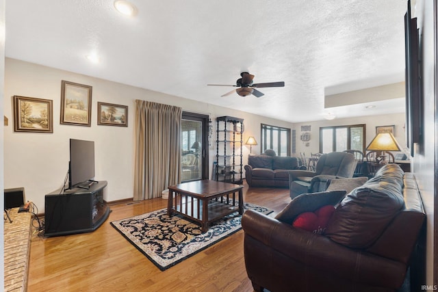 living room featuring hardwood / wood-style floors, ceiling fan, and a textured ceiling