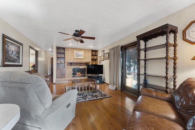 living room featuring a textured ceiling, ceiling fan, wood-type flooring, built in features, and a fireplace