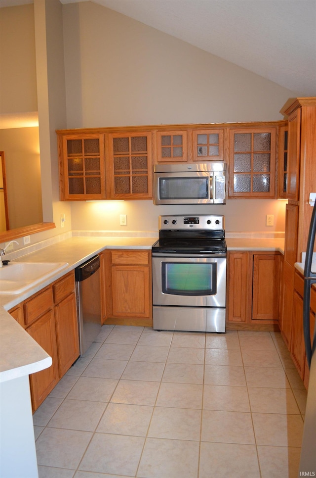 kitchen with sink, light tile patterned floors, lofted ceiling, and appliances with stainless steel finishes