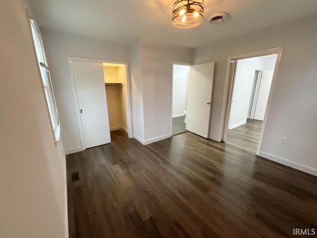 unfurnished bedroom with dark hardwood / wood-style floors, a walk in closet, and a closet