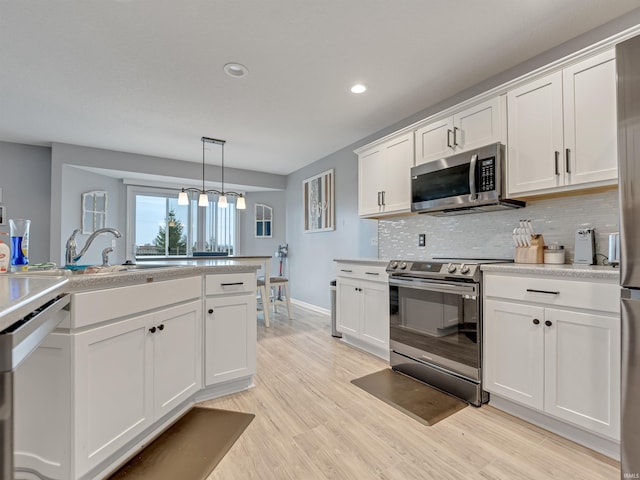 kitchen featuring light hardwood / wood-style floors, pendant lighting, decorative backsplash, white cabinets, and appliances with stainless steel finishes