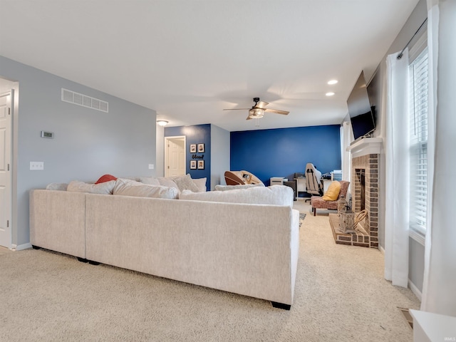 living room with ceiling fan, carpet, and a brick fireplace