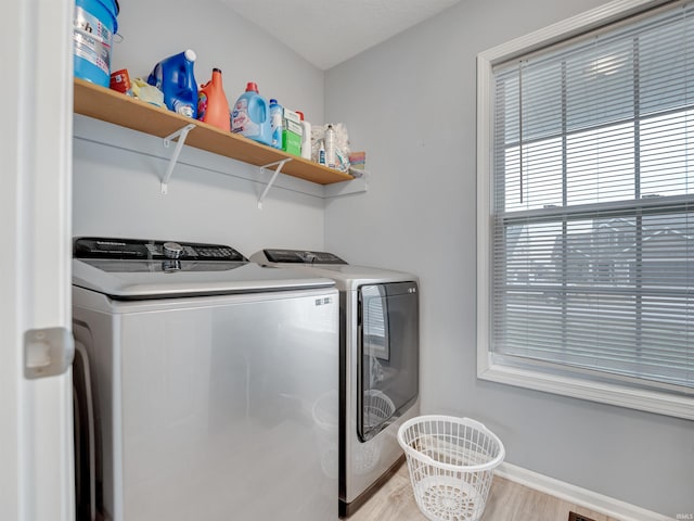 laundry room with washing machine and dryer and light hardwood / wood-style flooring