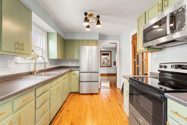 kitchen featuring appliances with stainless steel finishes, light hardwood / wood-style flooring, green cabinetry, and sink