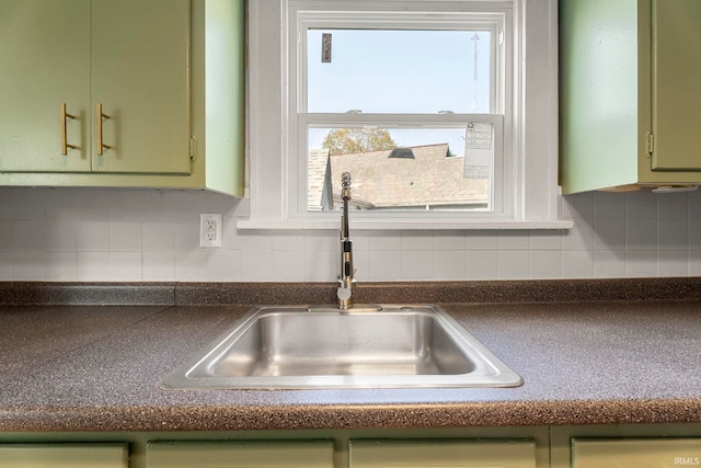 room details featuring backsplash, sink, and green cabinetry