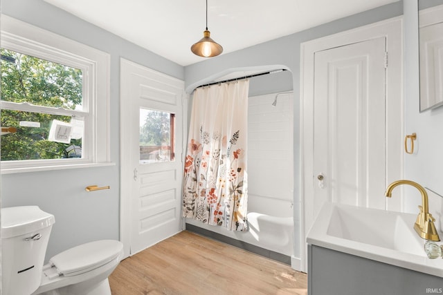 full bathroom featuring wood-type flooring, shower / bathtub combination with curtain, a wealth of natural light, and sink