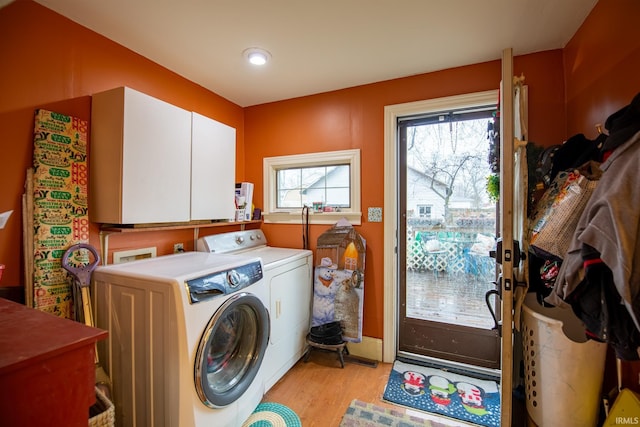 washroom with cabinets, light hardwood / wood-style flooring, and washer and dryer