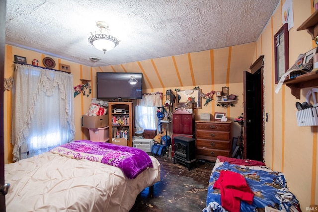 bedroom with a wood stove and a textured ceiling