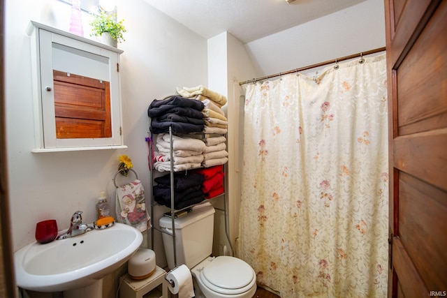 bathroom with a shower with shower curtain, toilet, and sink