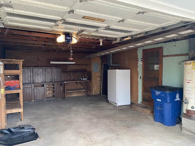 garage featuring electric panel, white fridge, a garage door opener, and water heater