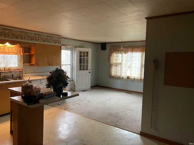 kitchen featuring a chandelier, light carpet, plenty of natural light, and hanging light fixtures