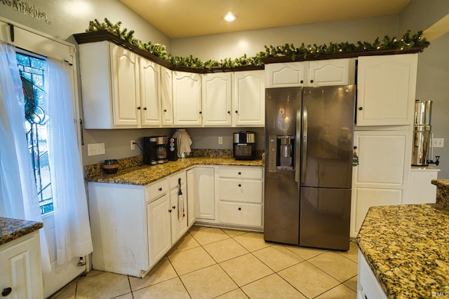 kitchen with white cabinets, light tile patterned floors, dark stone counters, and fridge with ice dispenser