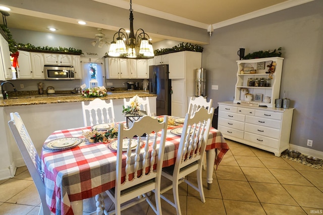 dining area with crown molding, sink, light tile patterned flooring, and an inviting chandelier