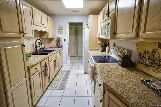 kitchen featuring sink, white appliances, a paneled ceiling, light brown cabinetry, and light tile patterned flooring