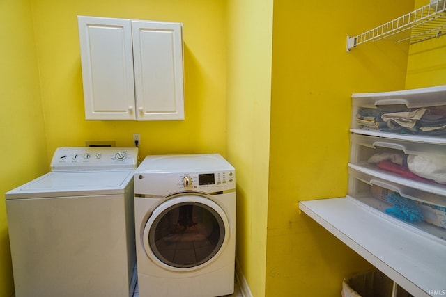 clothes washing area featuring cabinets and separate washer and dryer