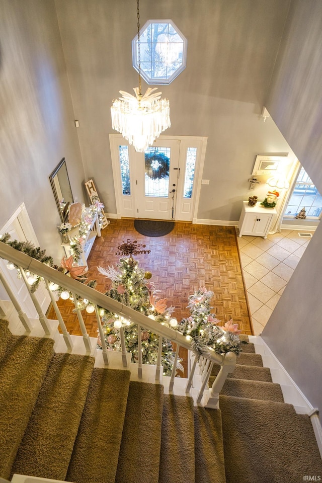 entrance foyer with tile patterned flooring, a towering ceiling, and a chandelier