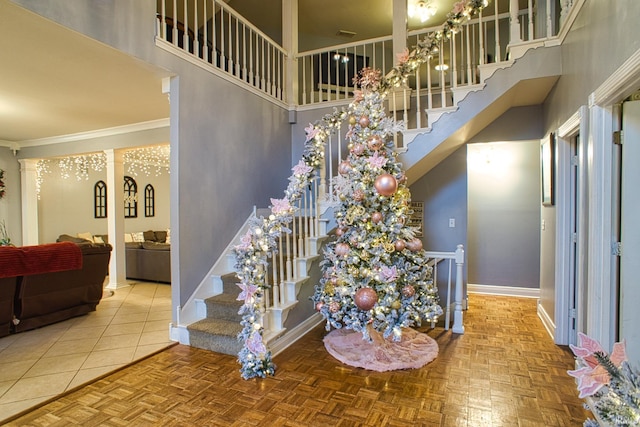 stairs featuring a towering ceiling, crown molding, and parquet flooring